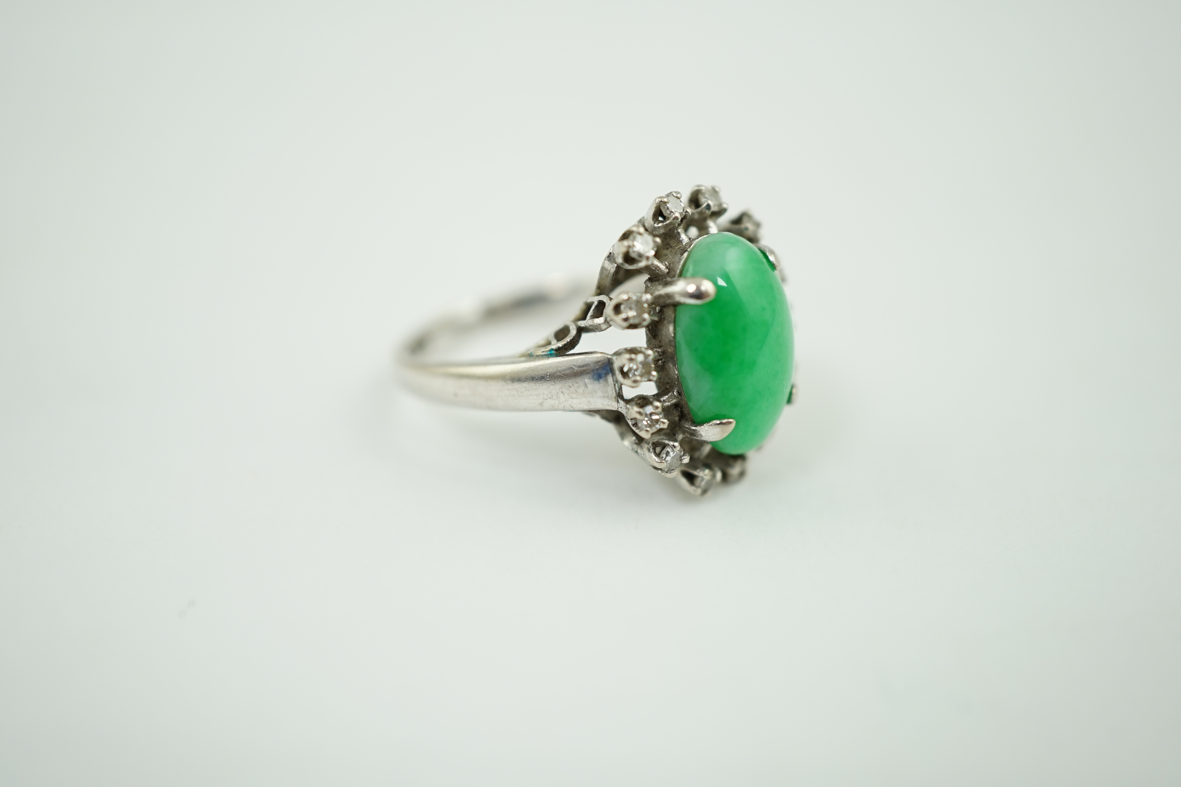 A white gold? and single stone oval cabochon jade set ring, with diamond set border